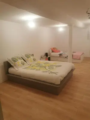 two beds in a room with wood floors at Maison de village in Ventenac-Cabardès