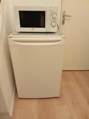 a microwave sitting on top of a refrigerator at Maison de village in Ventenac-Cabardès