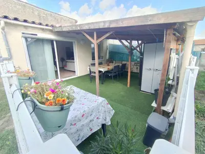 a patio with a table and flowers in buckets at Repos en campagne in Pexiora