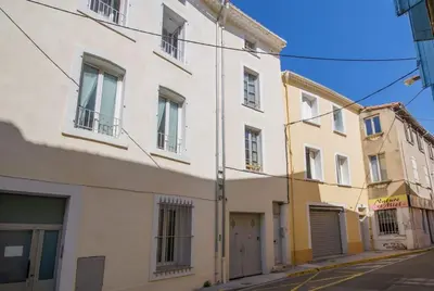 a white building on the side of a street at Logis des Barques YourHostHelper in Narbonne