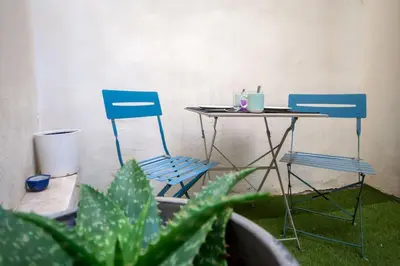 two blue chairs and a table and a table with a plant at Logis des Barques YourHostHelper in Narbonne
