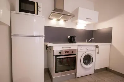 a kitchen with a refrigerator and a washing machine at Logis des Barques YourHostHelper in Narbonne