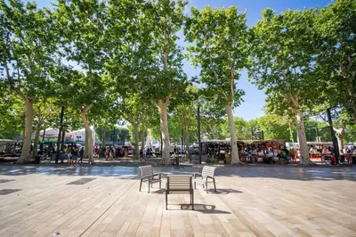 a park with two benches and trees and people at Logis des Barques YourHostHelper in Narbonne