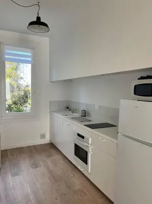 a white kitchen with a stove and a window at La maison de Camille climatisation parking privé WIFI in Carcassonne