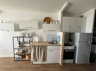 a kitchen with white cabinets and a sink and a refrigerator at Appartement vue mer, plage à 20m in Gruissan