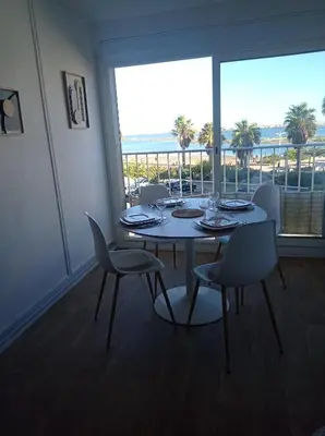 a dining room with a table and chairs and a large window at Appartement vue mer, plage à 20m in Gruissan