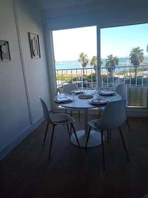 a dining room with a table and chairs and a large window at Appartement vue mer, plage à 20m in Gruissan