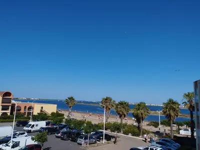 a parking lot with palm trees and a beach at Appartement vue mer, plage à 20m in Gruissan