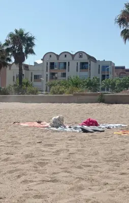 a person laying on a towel on the beach at Appartement vue mer, plage à 20m in Gruissan