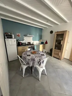 a kitchen with a table and chairs and a refrigerator at CHEZ COCO ET HERVE rez-de-chaussée in Sigean