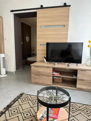a living room with a tv and a glass table at CHEZ COCO ET HERVE rez-de-chaussée in Sigean