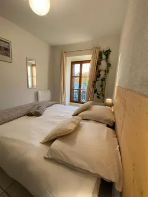 a bedroom with a large white bed with a window at Au pied de la cité, T3 au calme in Carcassonne