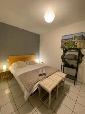 a bedroom with a bed with a bench and a painting at Au pied de la cité, T3 au calme in Carcassonne