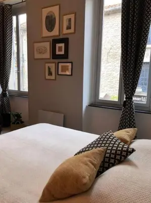 a bedroom with a white bed with two windows at Studio au pied de la cité in Carcassonne