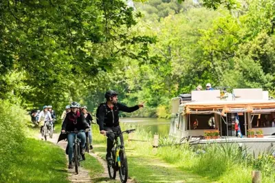 a group of people riding bikes down a path next to a boat at Studio au pied de la cité in Carcassonne