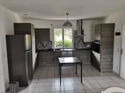 a kitchen with a table and a stainless steel refrigerator at La Maison du Bagas, 7pers in Vielmur-sur-Agout