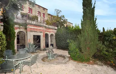 a garden with a table and a fountain in front of a building at Nice Home In Ventenac-En-Minervois in Ventenac en Minervois