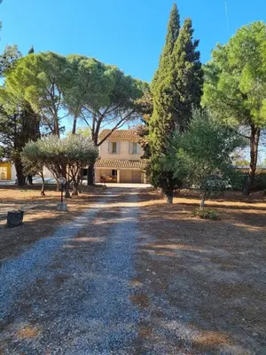 a driveway leading to a large house with trees at Mas de la vigne in Montredon
