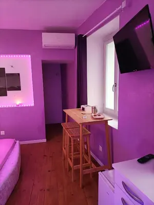 a purple room with a small table and a window at L'instant Romance : Le glamour in Castelnaudary