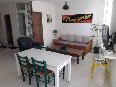 a living room with a table and chairs and a couch at Grand T3 calme et lumineux 4-6 personnes in Moux