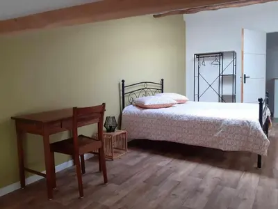 a bedroom with a bed and a table and a desk at Grand T3 calme et lumineux 4-6 personnes in Moux