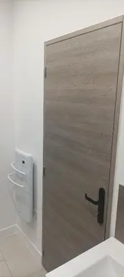 a wooden door in a bathroom with a dispenser at Grand T3 calme et lumineux 4-6 personnes in Moux