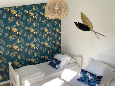 a bedroom with a bed and a wall with a butterfly wallpaper at Cosy T3 dans corps de ferme l écureuil in Vieillevigne