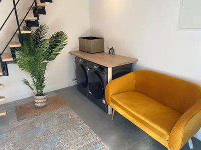 a living room with a yellow chair and a table at Cosy T3 dans corps de ferme l écureuil in Vieillevigne