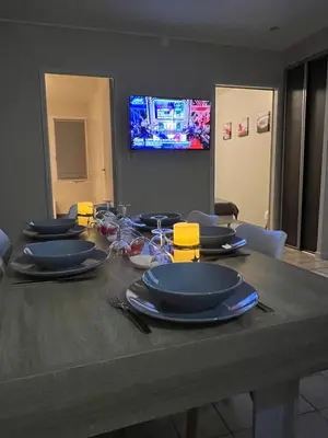 a dining room table with blue plates and a television at Plumes Résidence de l’Agout in Castres