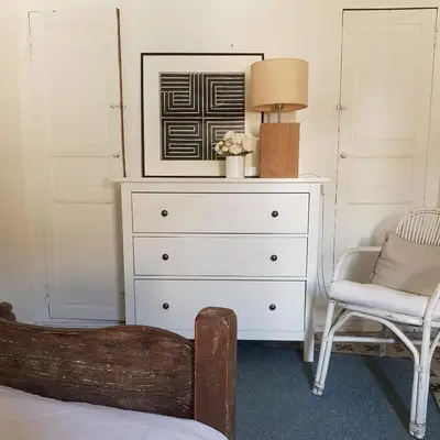 a bedroom with a dresser and a lamp and a chair at Petite maison de designer (avec terrasse) in Durban-Corbières