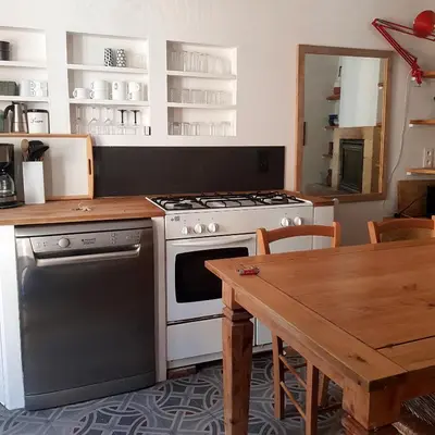 a kitchen with a stove and a wooden table at Petite maison de designer (avec terrasse) in Durban-Corbières