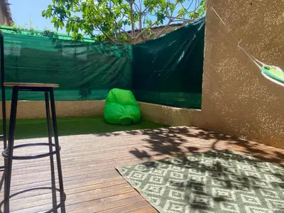 a wooden deck with a stool and a green bag at Confortable T2 avec jardin aménagé in Lézignan-Corbières