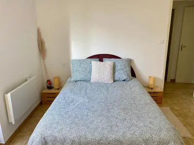 a bedroom with a bed with blue and white pillows at Confortable T2 avec jardin aménagé in Lézignan-Corbières