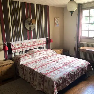 a bedroom with a bed with a red and white comforter at Maison chaleureuse à Cuxac-Cabardès avec jardin de 3500m² in Cuxac-Cabardès