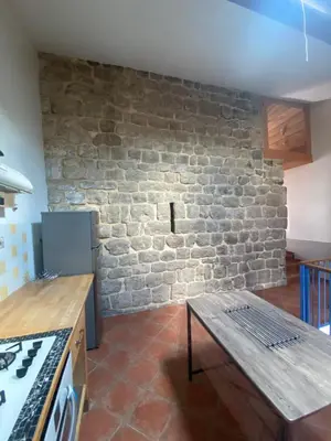 a kitchen with a brick wall and a wooden table at Domaine de Gourgounet gîte à la ferme, Gite de groupe 25 couchages avec piscine privative in Villefloure