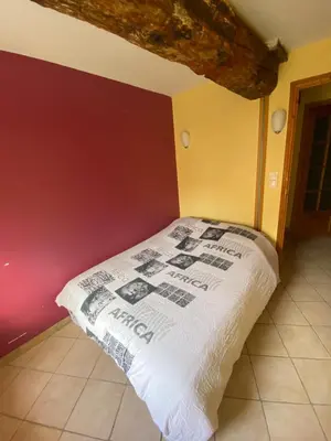 a bed in a room with a red wall at Domaine de Gourgounet gîte à la ferme, Gite de groupe 25 couchages avec piscine privative in Villefloure
