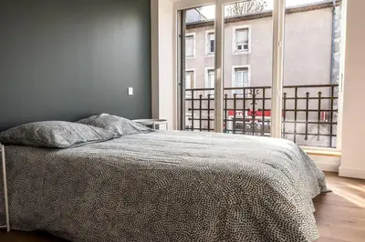 a bedroom with a bed and a large window at T2 Le Miredames in Castres