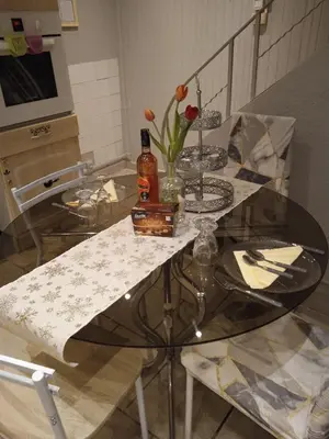 a glass table with a bottle of alcohol and flowers on it at Jolie maison de village in Capendu