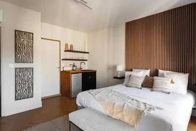 a bedroom with a large white bed with a wooden headboard at L'Évêché/ Clim/ Vue/ Confort in Carcassonne