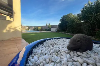 a bird statue in a bed of rocks in a backyard at La Flemme en Rose- Villa avec piscine-Pet Friendly in Peyriac-de-Mer