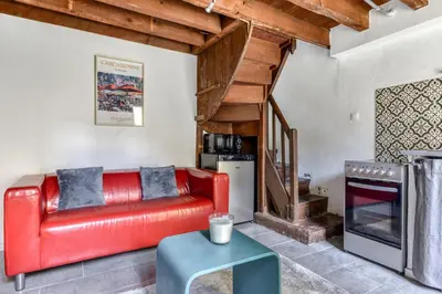 a living room with a red couch and a table at Le Patio de la Bastide avec Terrasse & Netflix - Quartier paisible in Carcassonne