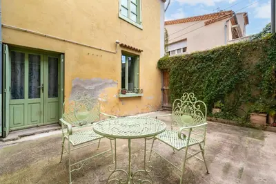a patio with a table and chairs in front of a building at Le Patio de la Bastide avec Terrasse & Netflix - Quartier paisible in Carcassonne