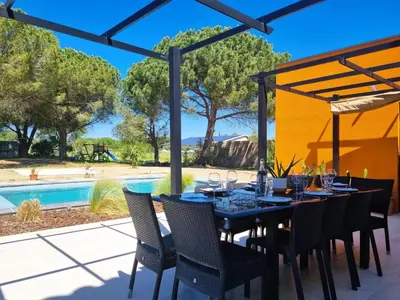 a dining room with a table and chairs and a pool at Le Catamaran in Sallèles-dʼAude