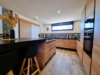 a kitchen with a black counter and wooden cabinets at Le Catamaran in Sallèles-dʼAude