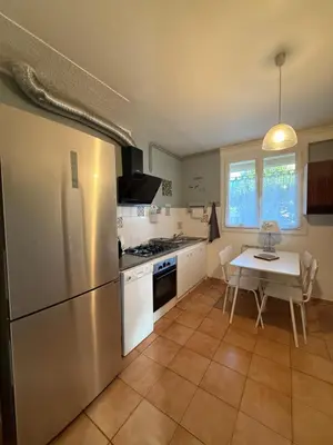 a kitchen with a stainless steel refrigerator and a table at escapade près du lac in Peyriac-de-Mer