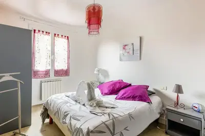 a white bedroom with a bed with purple pillows at escapade près du lac in Peyriac-de-Mer