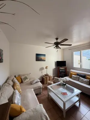 a living room with couches and a ceiling fan at escapade près du lac in Peyriac-de-Mer