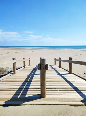 a wooden boardwalk on the beach with the ocean at L'Escapade : Charmant T2 -Parking gratuit, piscine, wifi, clim in Gruissan