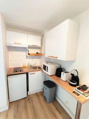 a kitchen with white cabinets and a wooden counter top at L'Escapade : Charmant T2 -Parking gratuit, piscine, wifi, clim in Gruissan