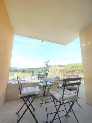 a balcony with a table and chairs and a large window at L'Escapade : Charmant T2 -Parking gratuit, piscine, wifi, clim in Gruissan